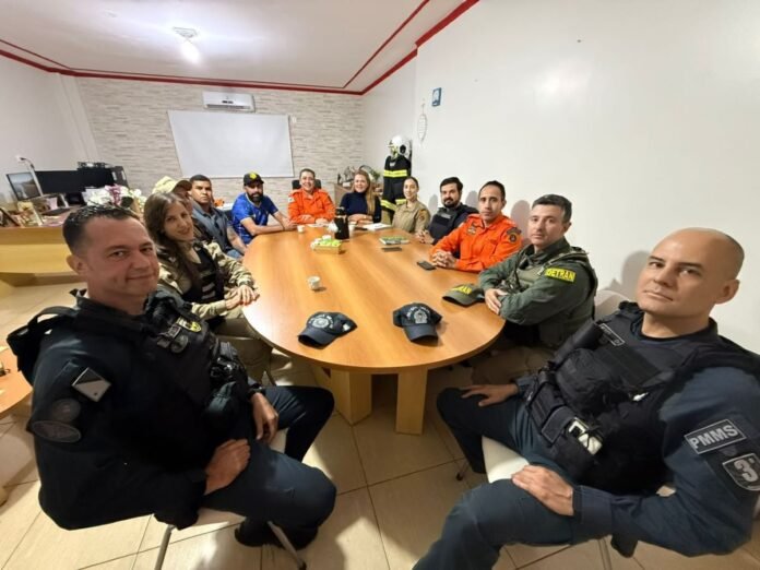Group of uniformed officers and civilians seated around a wooden conference table in a briefing room.