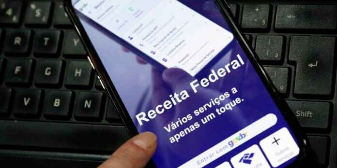 Smartphone screen displaying the Portuguese 'Receita Federal' app on a keyboard surface