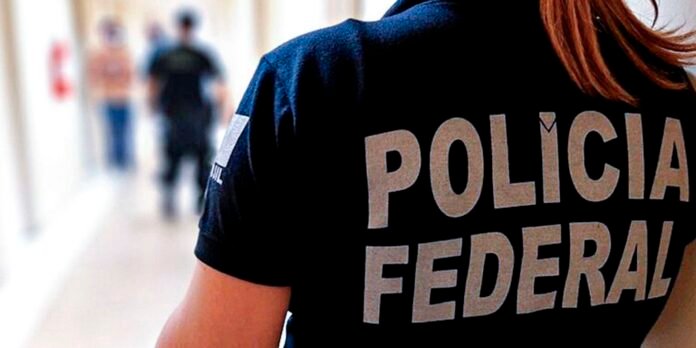 Back of a person wearing a dark shirt with the words 'POLICIA FEDERAL' printed in large letters on the jacket.