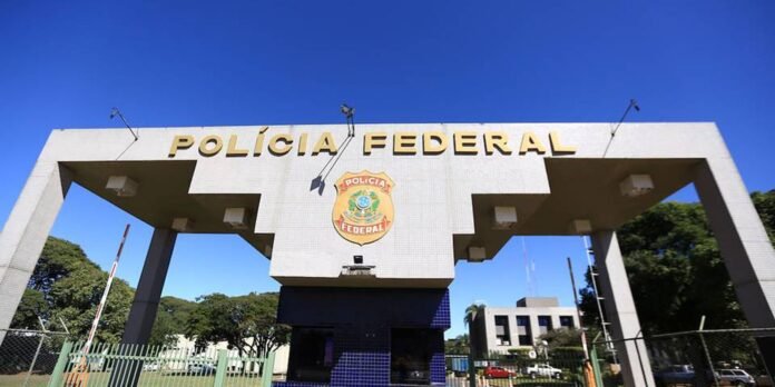Federal Police entrance arch with emblem and bold 'POLÍCIA FEDERAL' lettering against a clear blue sky in Brazil.