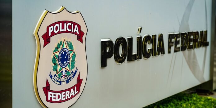 Brazilian Federal Police emblem on a wall with 'POLÍCIA FEDERAL' text beside it (signage outside a police building)