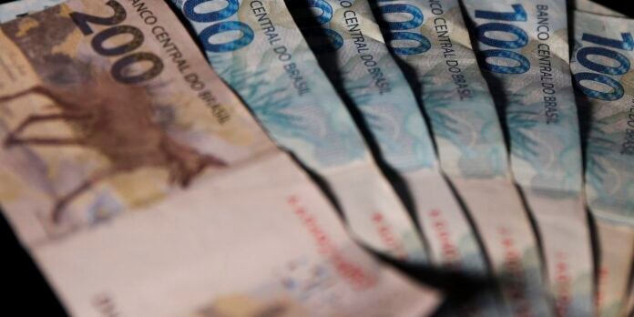 Fanned Brazilian banknotes featuring blue 100 reais and brown 200 reais denominations, arranged in a roll showing security patterns
