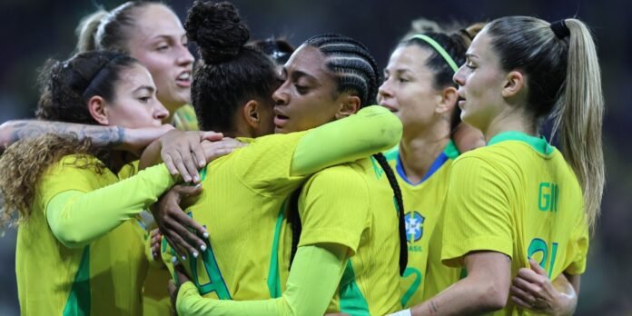 Brazilian women’s soccer team huddling in yellow jerseys, celebrating on the field during a match.