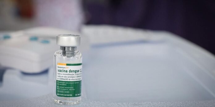 Vial of dengue vaccine on a sterile medical table with a blurred background.
