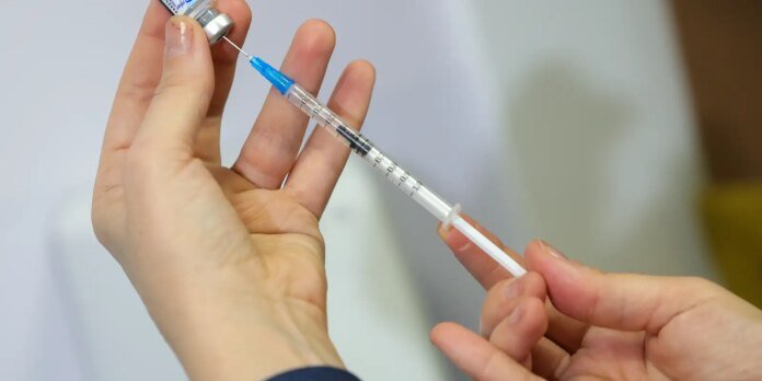 Medical professional drawing liquid from a vial into a syringe.