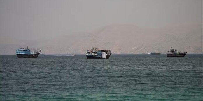 Several boats anchored on calm turquoise sea with hazy arid hills in the background