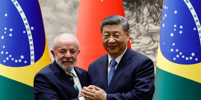 Two world leaders in dark suits shake hands in front of Brazil and China banners at a formal meeting.