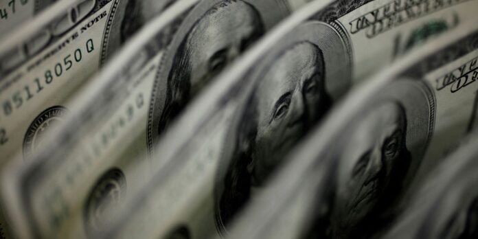 Close-up of US dollar bills with Benjamin Franklin's portrait partially visible among folded notes, emphasizing money.