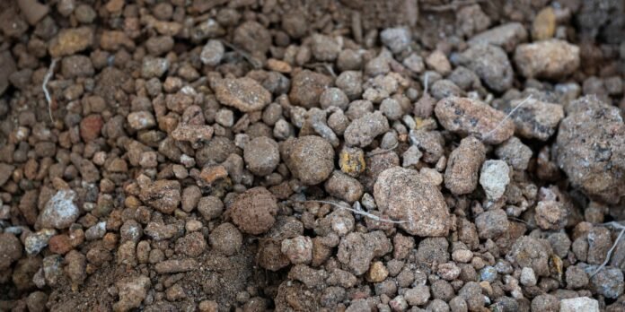 Close-up of dry brown gravel and small rocky soil particles scattered on the ground