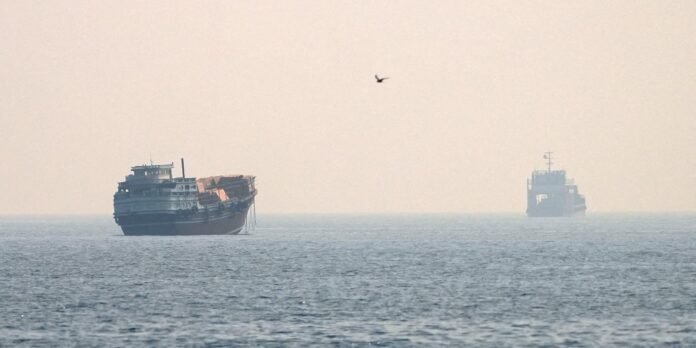 Two large ships sit on a calm sea with a hazy horizon; a distant vessel is to the right and a lone bird flies above.