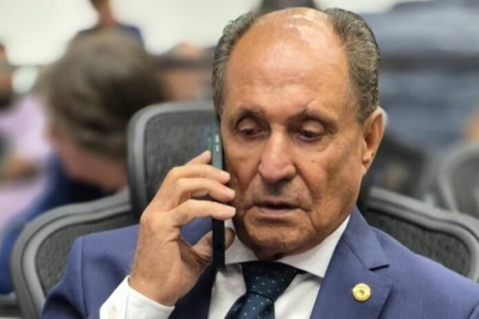 Older man in a navy suit talking on a cell phone in an office setting