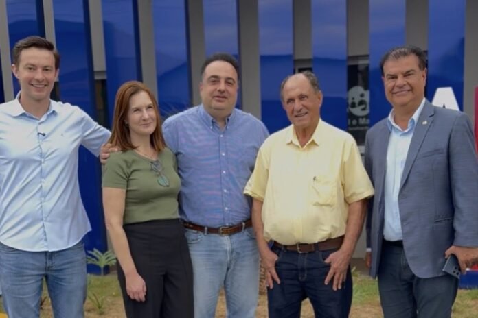 Five adults standing together outside a blue building, smiling at the camera.