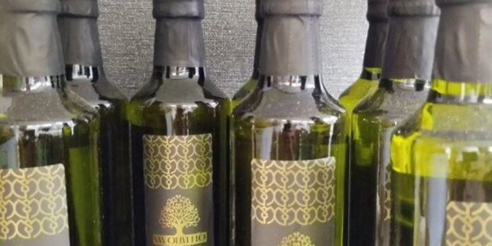 Row of green wine bottles with gold patterned labels and foil necks.