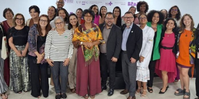 Large group of diverse professionals posing together indoors for a group photo.