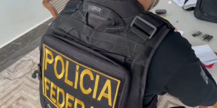 Police officer wearing a black tactical vest with a large yellow POLICIA FEDERAL patch on the back, showing MOLLE straps.