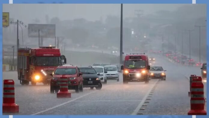 Flooded highway with vehicles driving through heavy rain; two red fire trucks and a red SUV in the foreground, orange traffic cones along the road.