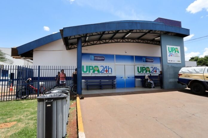 Front view of a blue-and-white medical clinic with UPA 24h signage and people outside near the entrance.