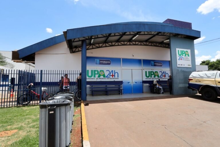 Front view of a blue-and-white medical clinic with UPA 24h signage and people outside near the entrance.
