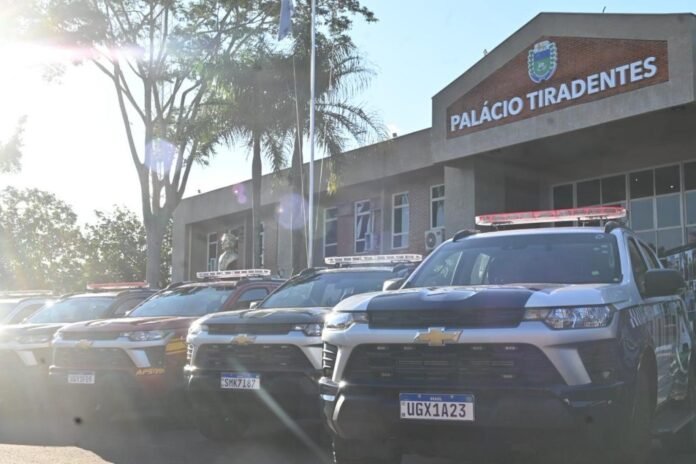 Several police SUVs lined up outside the Palácio Tiradentes on a sunny day, with glare from the sun in the foreground.