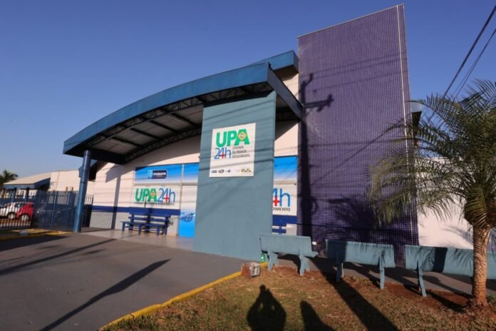 Front of a UPA 24h urgent care center with blue facade, curved roof, and blue benches outside.
