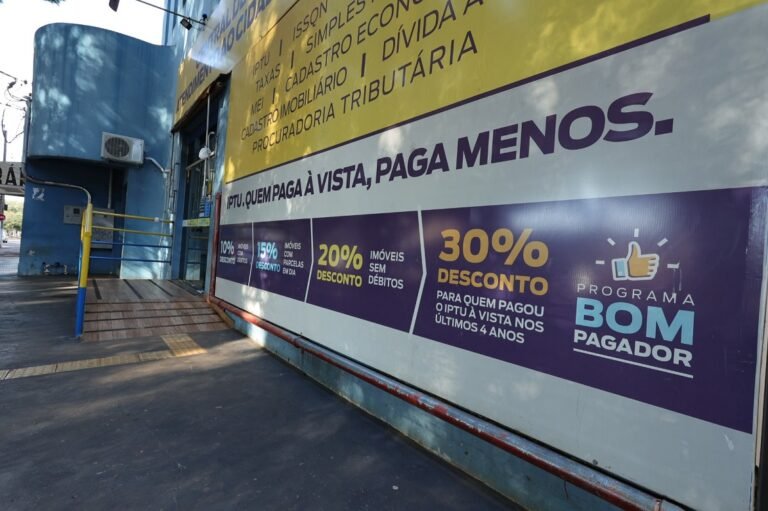 Storefront with large yellow and purple banners advertising discounts, including '30% DESCONTO' and 'PROGRAMA BOM PAGADOR'.