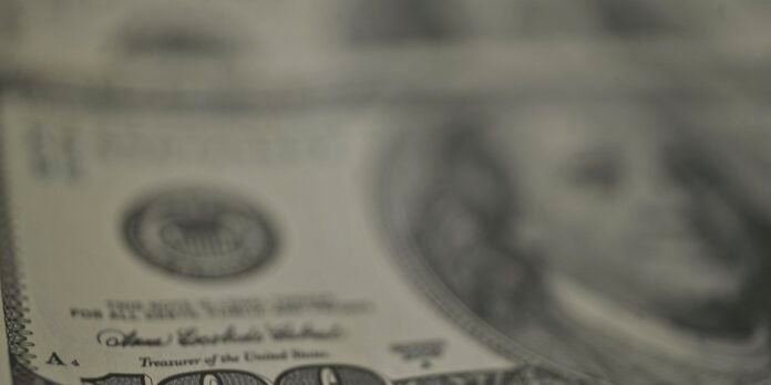 Close-up of a US dollar bill focusing on the Treasury seal and 'Treasurer of the United States' text (blurry detail).