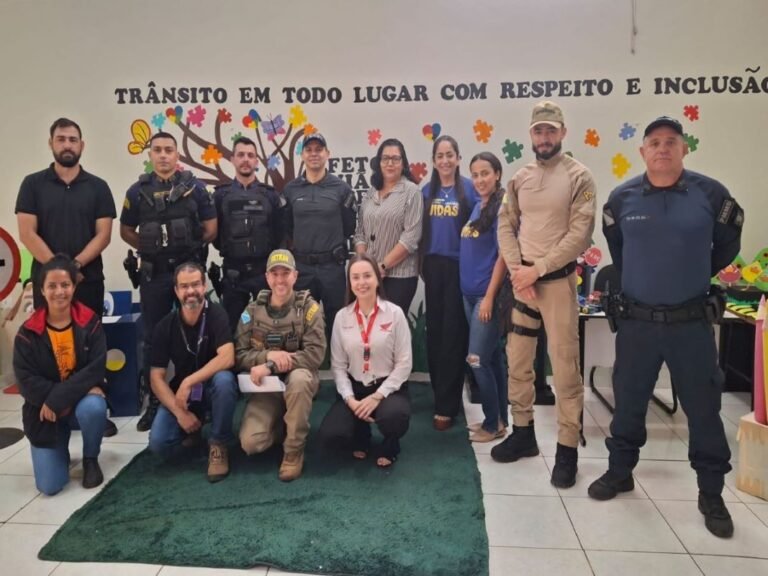 Group of uniformed officers and civilians posing indoors in front of a colorful mural about inclusive traffic safety.