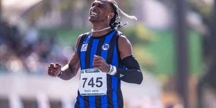 Male runner in a blue and black striped jersey wearing bib 745 mid-race, expression intense and hands clenched
