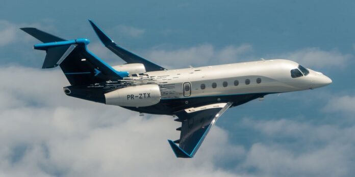 Private business jet inverted in flight, white fuselage with blue accents and registration PR-ZTX visible.