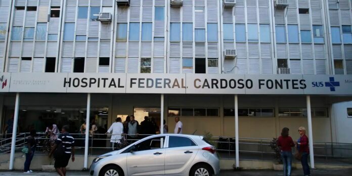 Facade of Hospital Federal Cardoso Fontes with a crowd outside the entrance and a silver car in front.