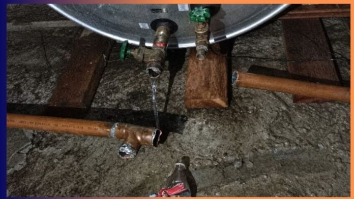 Water heater with leaking pipe connections dripping onto a concrete basement floor.