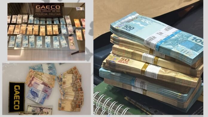 Stacks of Brazilian reais on a table with a GAECO Polícia Militar sign in the background