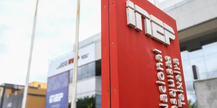 Red vertical sign with large white 3D letters mounted on a modern glass-front building, advertising a company in a business district (text not fully legible).