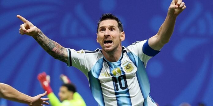 Argentine soccer player in blue-and-white striped jersey celebrating with arms raised.