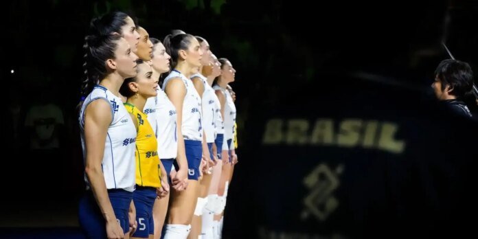 Lineup of female volleyball players in white and yellow jerseys standing in a row during a pre-game ceremony, facing the coach on the right