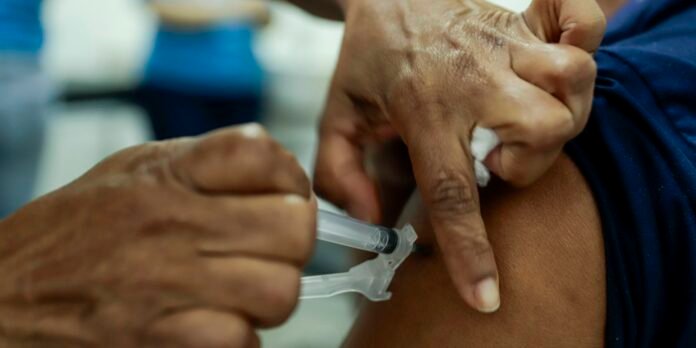 Healthcare worker administering a vaccine into a person’s upper arm (close-up).