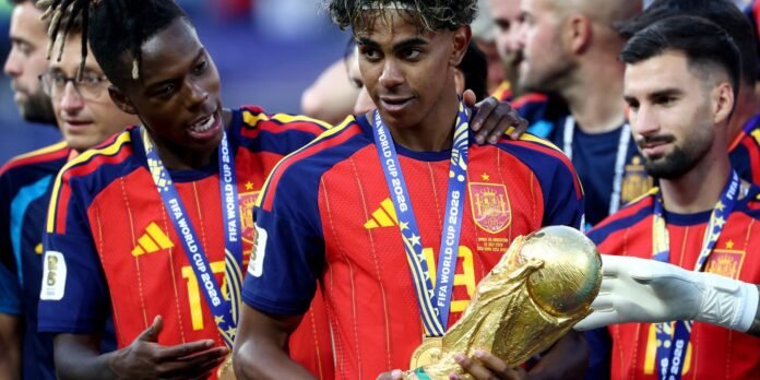Spanish soccer players pose with medals and a golden World Cup trophy after a win