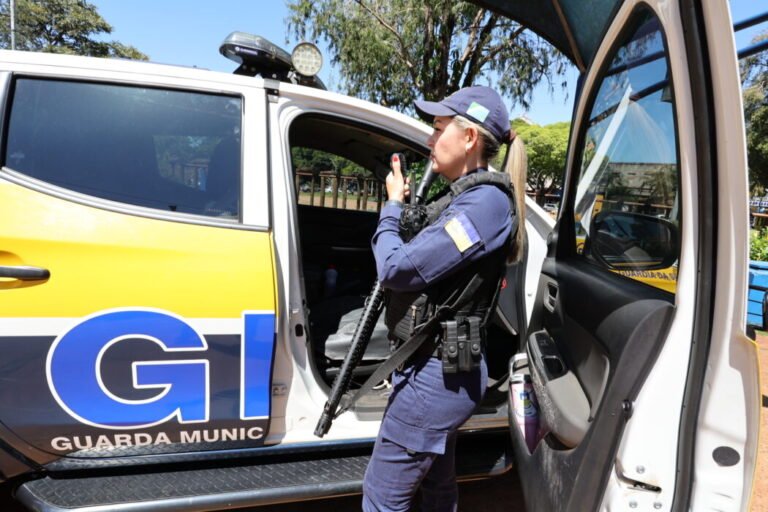 Female officer from Guardia Municipal standing by an open car door, holding a radio mic.