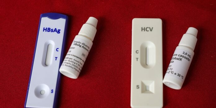 Two rapid hepatitis tests (HBsAg and HCV) with dropper bottles on red fabric behind them.