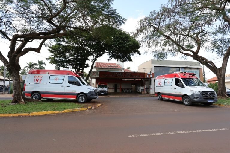 Two red-and-white ambulances labeled SAMU 192 parked in front of a hospital entrance under large trees.