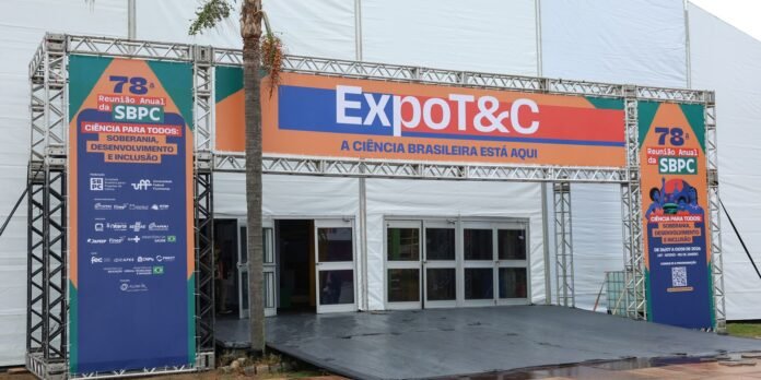 Entrance to ExpoT&C science exposition with orange-blue banners and SBPC panels flanking a metal frame archway.