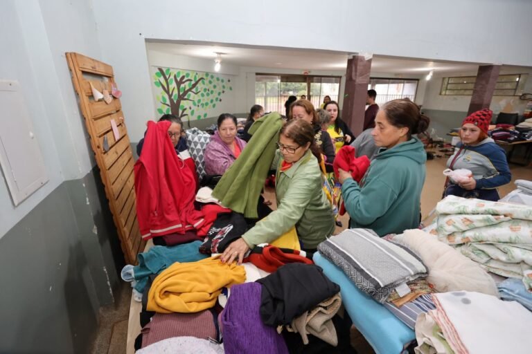 Group of volunteers sorting and stacking donated clothes on tables in a community center.