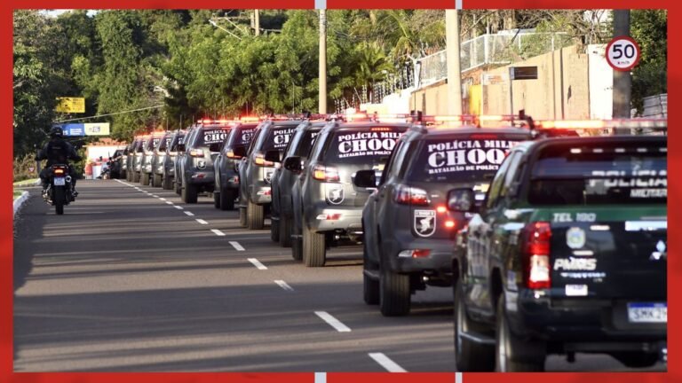 Line of police SUVs with flashing lights on a city street, forming a convoy under leafy trees.