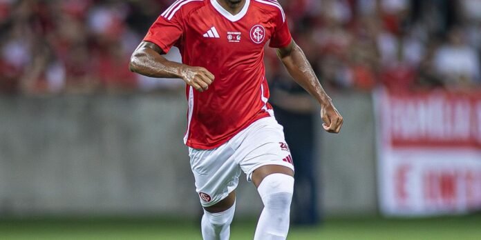 Soccer player in a red jersey and white shorts sprinting on the field during a match