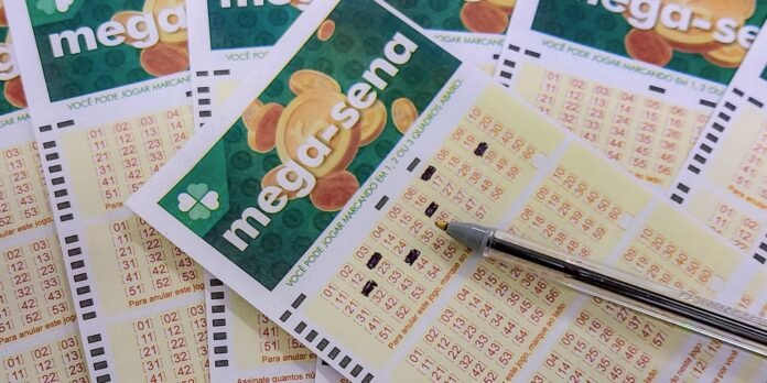 Multiple Mega-Sena lottery tickets with orange number grids and a black pen resting on one, on top of a colorful green background.