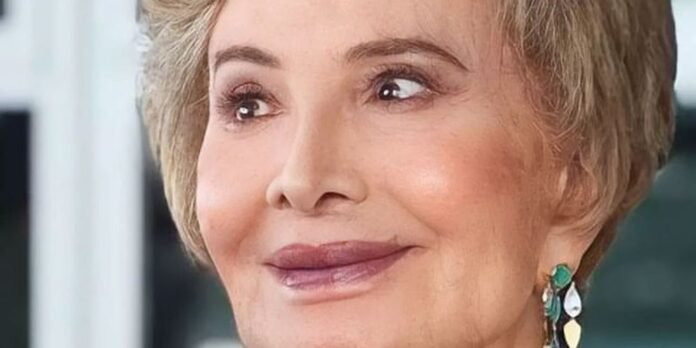Close-up of a smiling woman with short blond hair and colorful teardrop earrings.