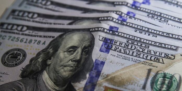 Fanned stack of U.S. one hundred dollar bills featuring Benjamin Franklin portrait.