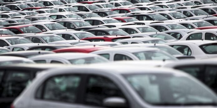 Crowded parking lot filled with rows of white cars and a few red vehicles interspersed throughout.