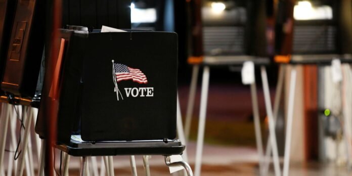 Black voting booth with an American flag graphic and the word VOTE in a polling place.