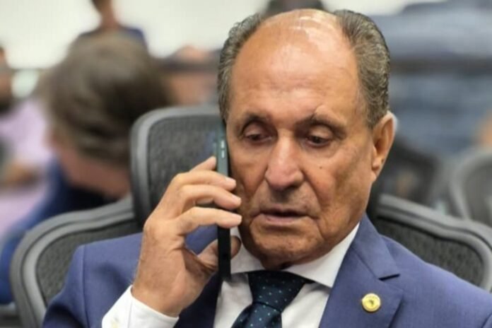 Man in a blue suit on a smartphone during a meeting, looking focused and serious.